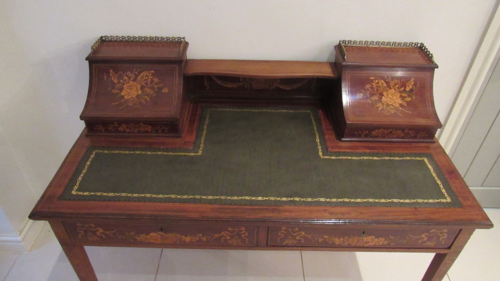 An Edwardian mahogany writing desk featuring detailed floral marquetry inlays, a green leather top, and raised stationery boxes with brass galleries. View VII