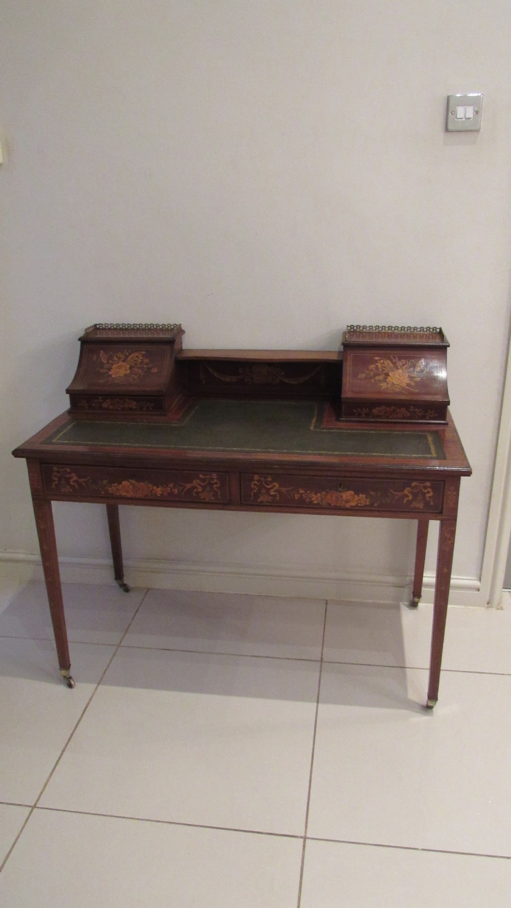 An Edwardian mahogany writing desk featuring detailed floral marquetry inlays, a green leather top, and raised stationery boxes with brass galleries. View XVII