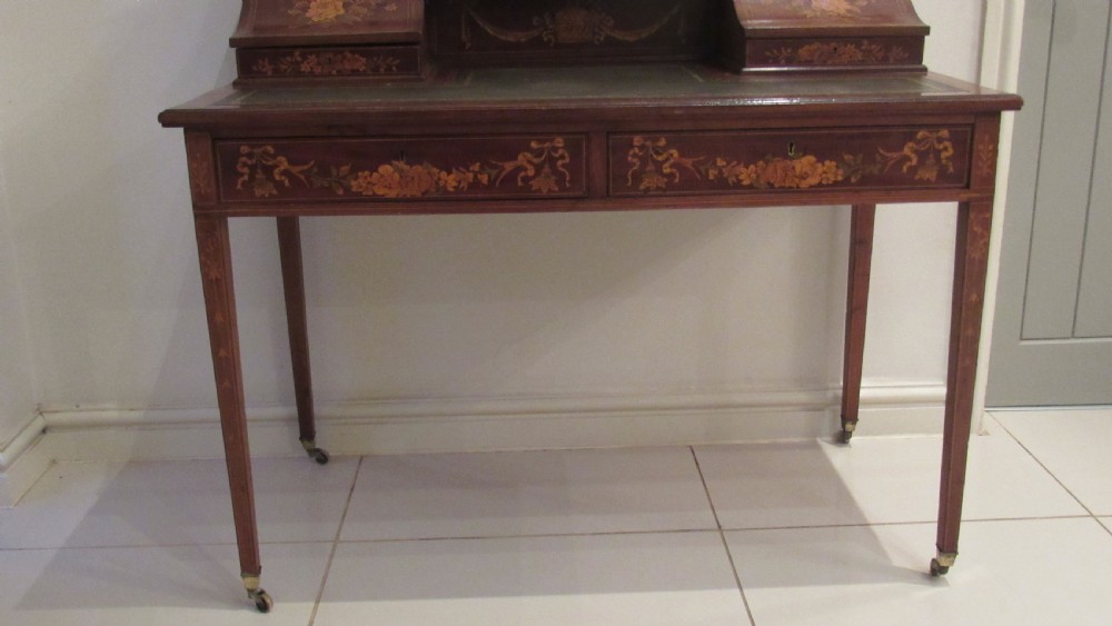 An Edwardian mahogany writing desk featuring detailed floral marquetry inlays, a green leather top, and raised stationery boxes with brass galleries. View XX