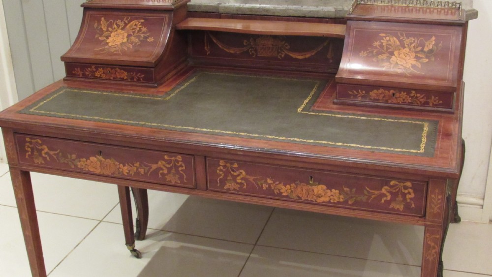 An Edwardian mahogany writing desk featuring detailed floral marquetry inlays, a green leather top, and raised stationery boxes with brass galleries. View XXII