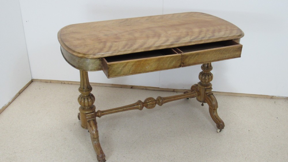 A Victorian satin walnut library table featuring a rectangular top with rounded corners, a pulled-out frieze drawer, turned pedestal legs, and a low central stretcher base.