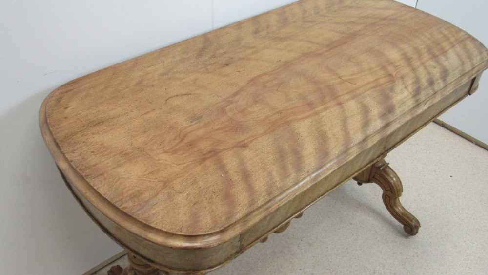 A Victorian satin walnut library table featuring a rectangular top with rounded corners, a pulled-out frieze drawer, turned pedestal legs, and a low central stretcher base. View II