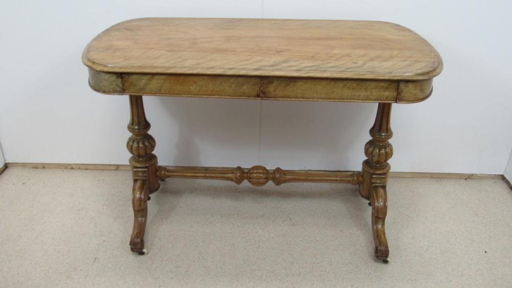 A Victorian satin walnut library table featuring a rectangular top with rounded corners, a pulled-out frieze drawer, turned pedestal legs, and a low central stretcher base. View III