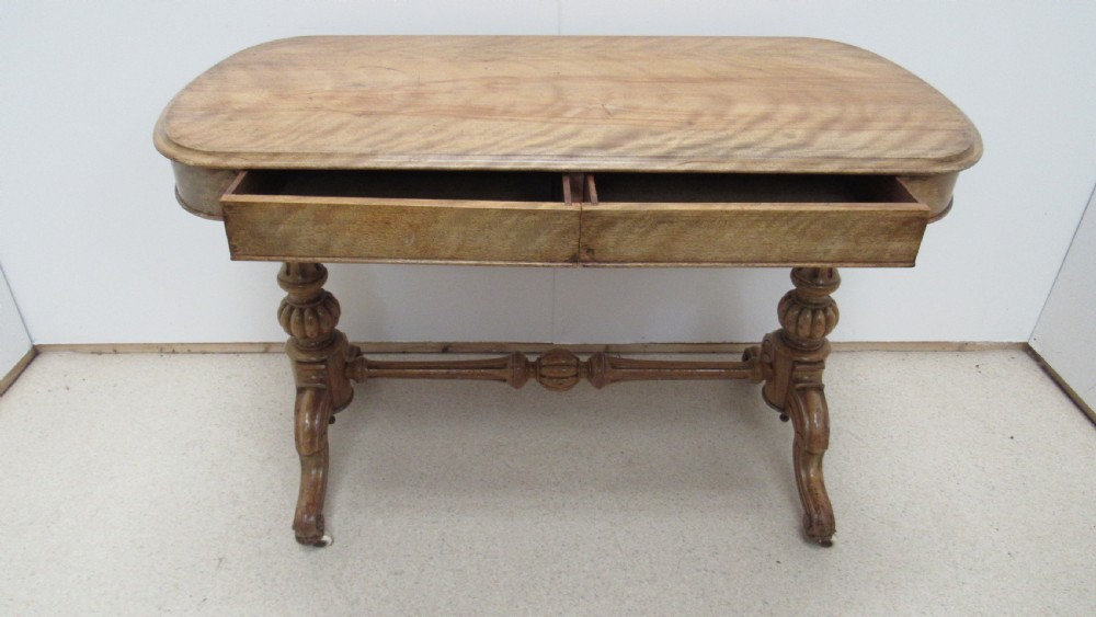 A Victorian satin walnut library table featuring a rectangular top with rounded corners, a pulled-out frieze drawer, turned pedestal legs, and a low central stretcher base. View V