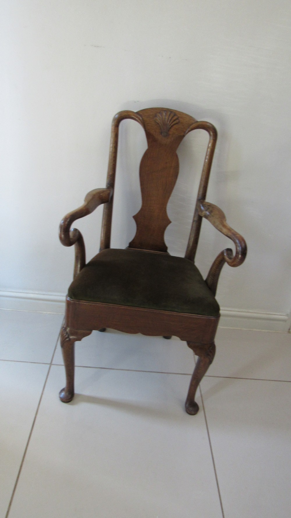 A miniature Queen Anne style childs armchair crafted from dark wood with a carved shell top rail, vasiform splat back, cabriole front legs, and a dark green velvet padded seat.