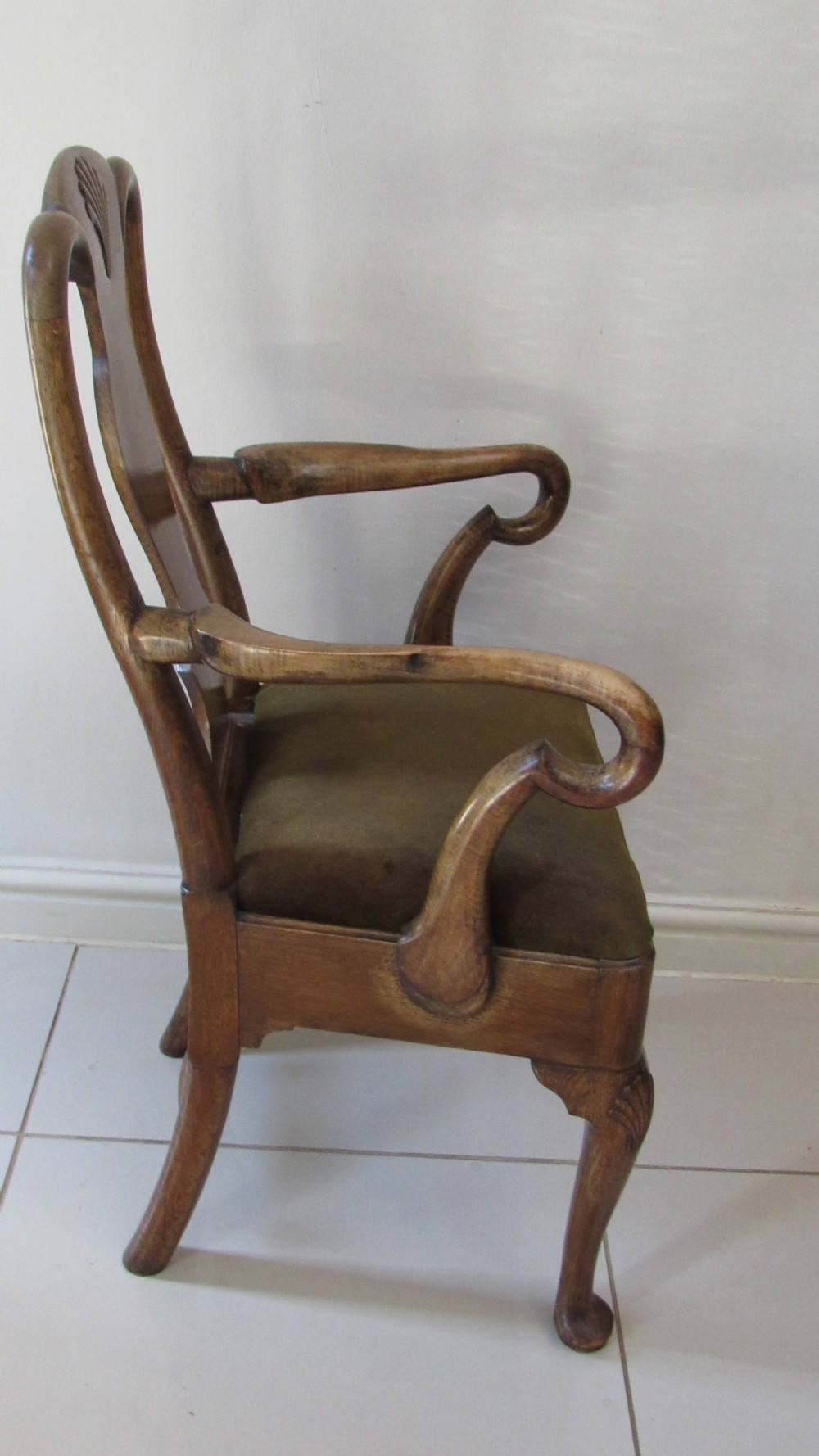 A miniature Queen Anne style childs armchair crafted from dark wood with a carved shell top rail, vasiform splat back, cabriole front legs, and a dark green velvet padded seat. View VII