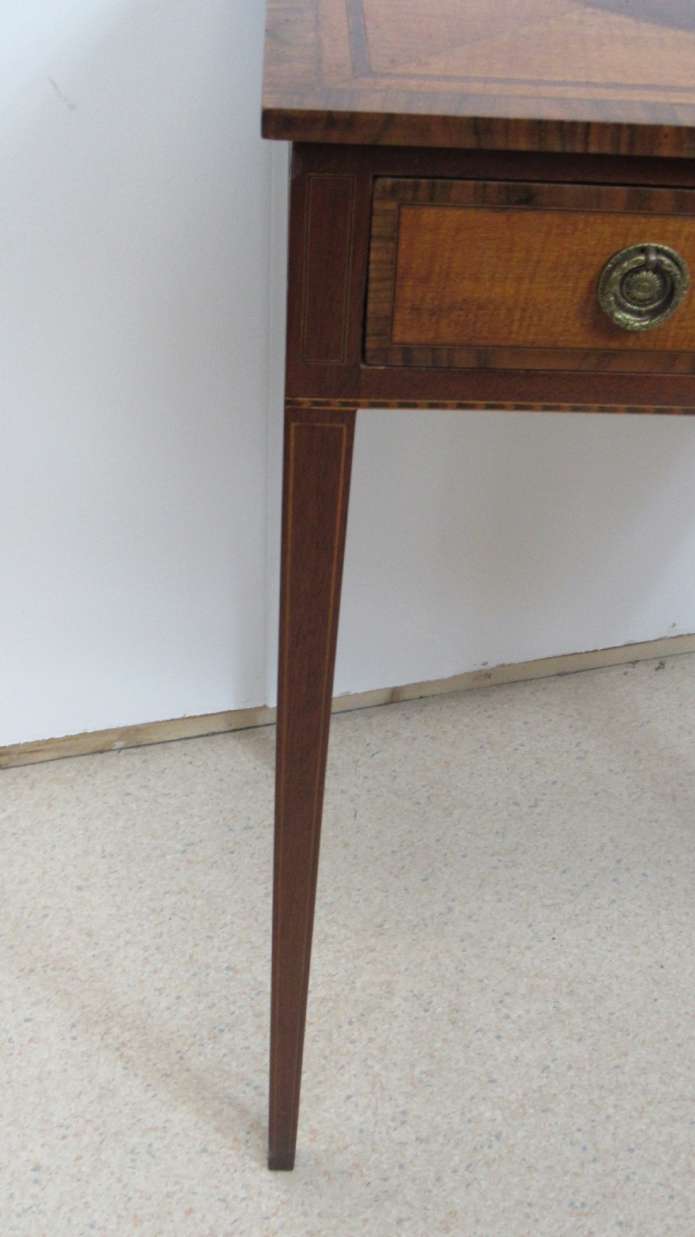 A 19th-century wooden side table featuring square tapered legs, a single drawer with brass handles, and a decorative oval inlaid top surface. View III