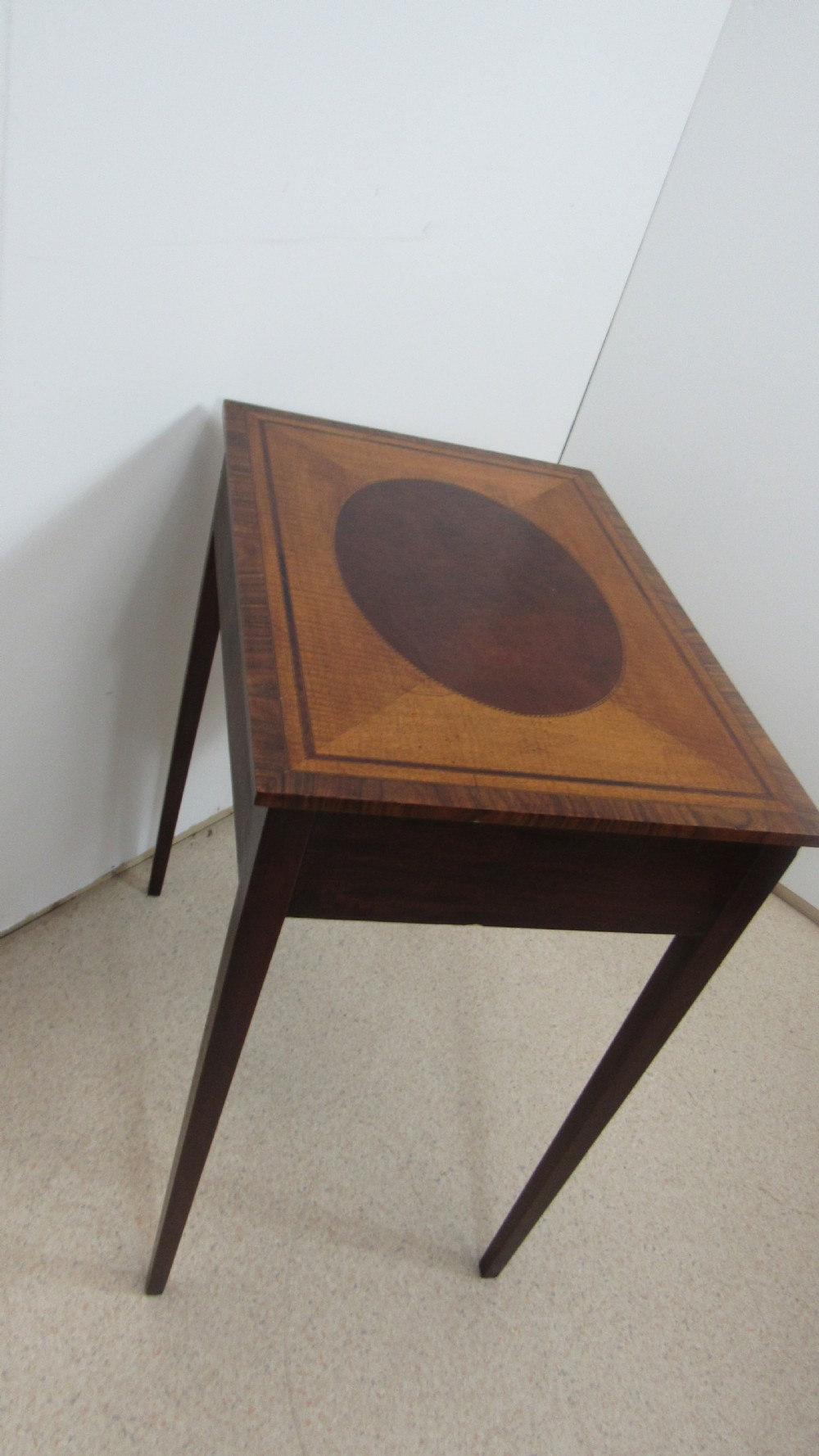 A 19th-century wooden side table featuring square tapered legs, a single drawer with brass handles, and a decorative oval inlaid top surface. View VIII