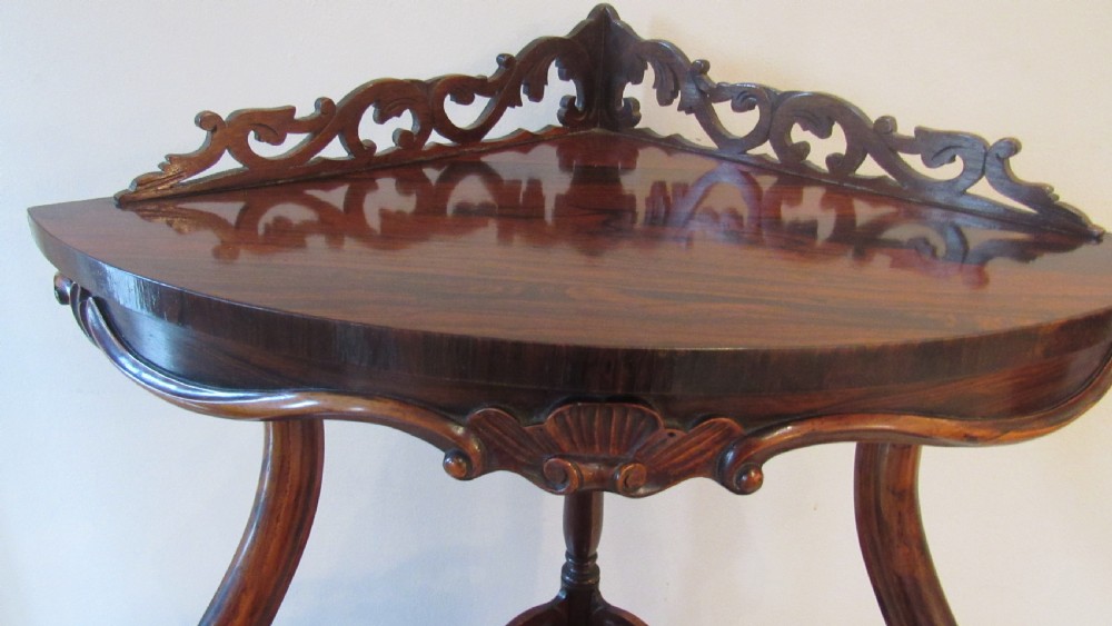 A three-tiered Victorian rosewood corner whatnot featuring intricate carved fretwork galleries, serpentine supports, and small carved feet. View III
