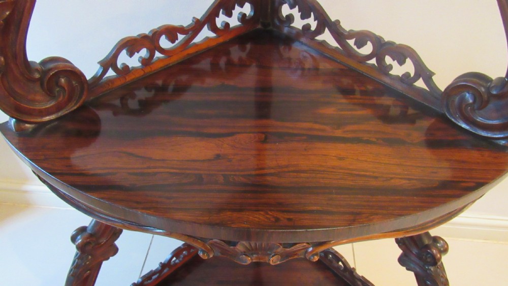 A three-tiered Victorian rosewood corner whatnot featuring intricate carved fretwork galleries, serpentine supports, and small carved feet. View IV