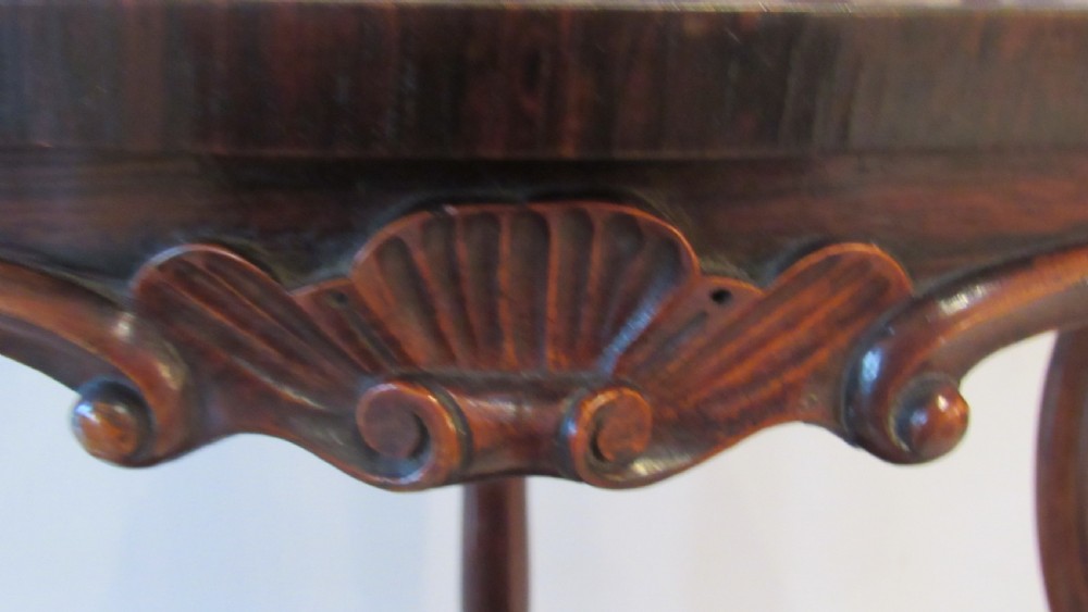 A three-tiered Victorian rosewood corner whatnot featuring intricate carved fretwork galleries, serpentine supports, and small carved feet. View VI
