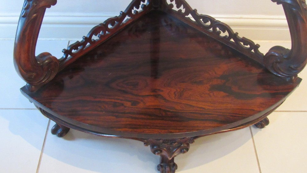 A three-tiered Victorian rosewood corner whatnot featuring intricate carved fretwork galleries, serpentine supports, and small carved feet. View VII