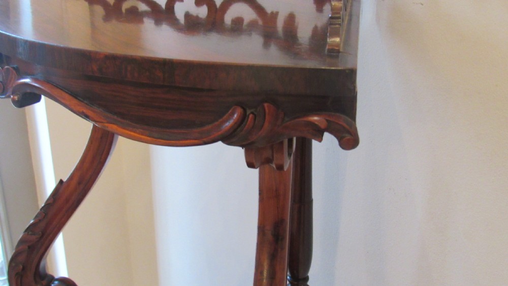 A three-tiered Victorian rosewood corner whatnot featuring intricate carved fretwork galleries, serpentine supports, and small carved feet. View XVI