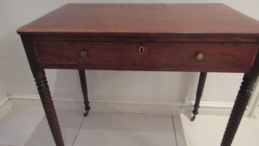 A Georgian mahogany chamber table featuring a rectangular top with a central flap, a single frieze drawer with brass hardware, and spiral turned legs on brass castors. View IX