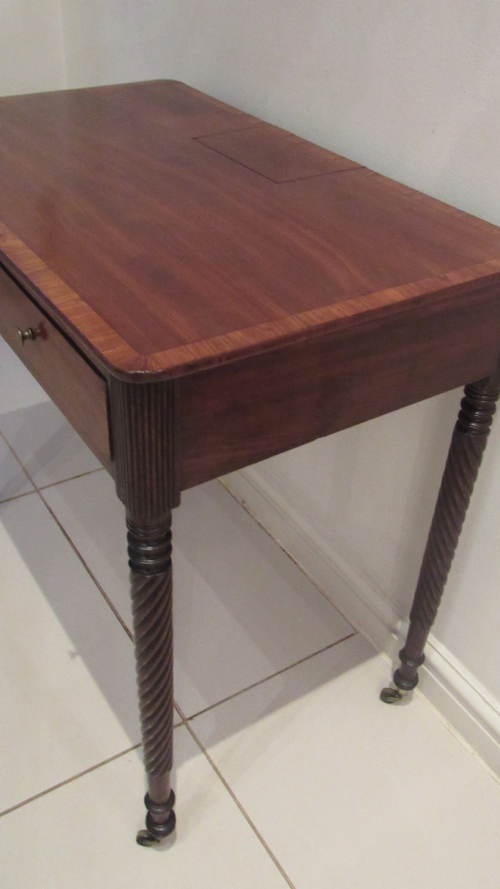 A Georgian mahogany chamber table featuring a rectangular top with a central flap, a single frieze drawer with brass hardware, and spiral turned legs on brass castors. View XIII