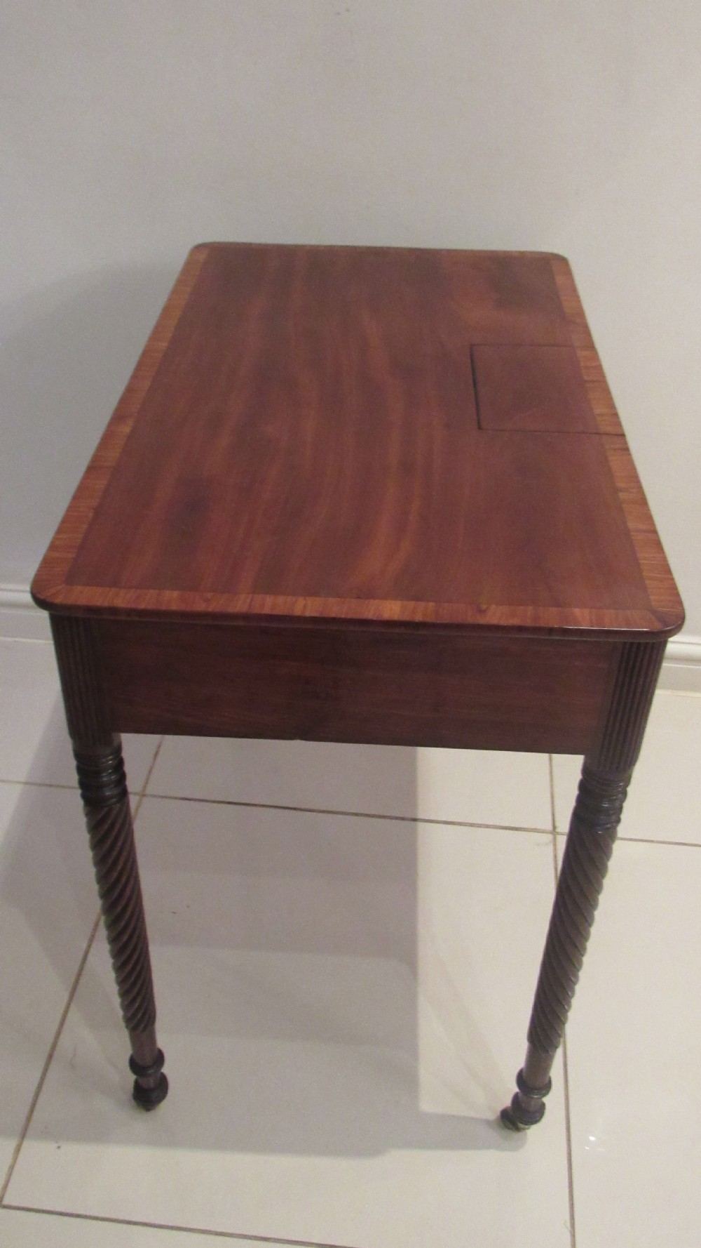 A Georgian mahogany chamber table featuring a rectangular top with a central flap, a single frieze drawer with brass hardware, and spiral turned legs on brass castors. View XIV