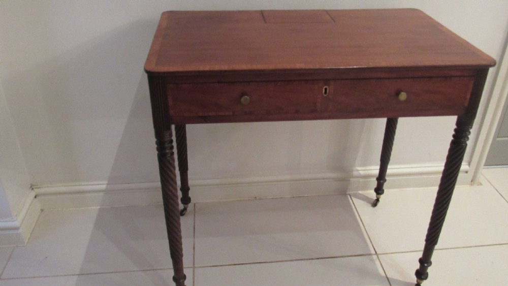 A Georgian mahogany chamber table featuring a rectangular top with a central flap, a single frieze drawer with brass hardware, and spiral turned legs on brass castors. View XVI