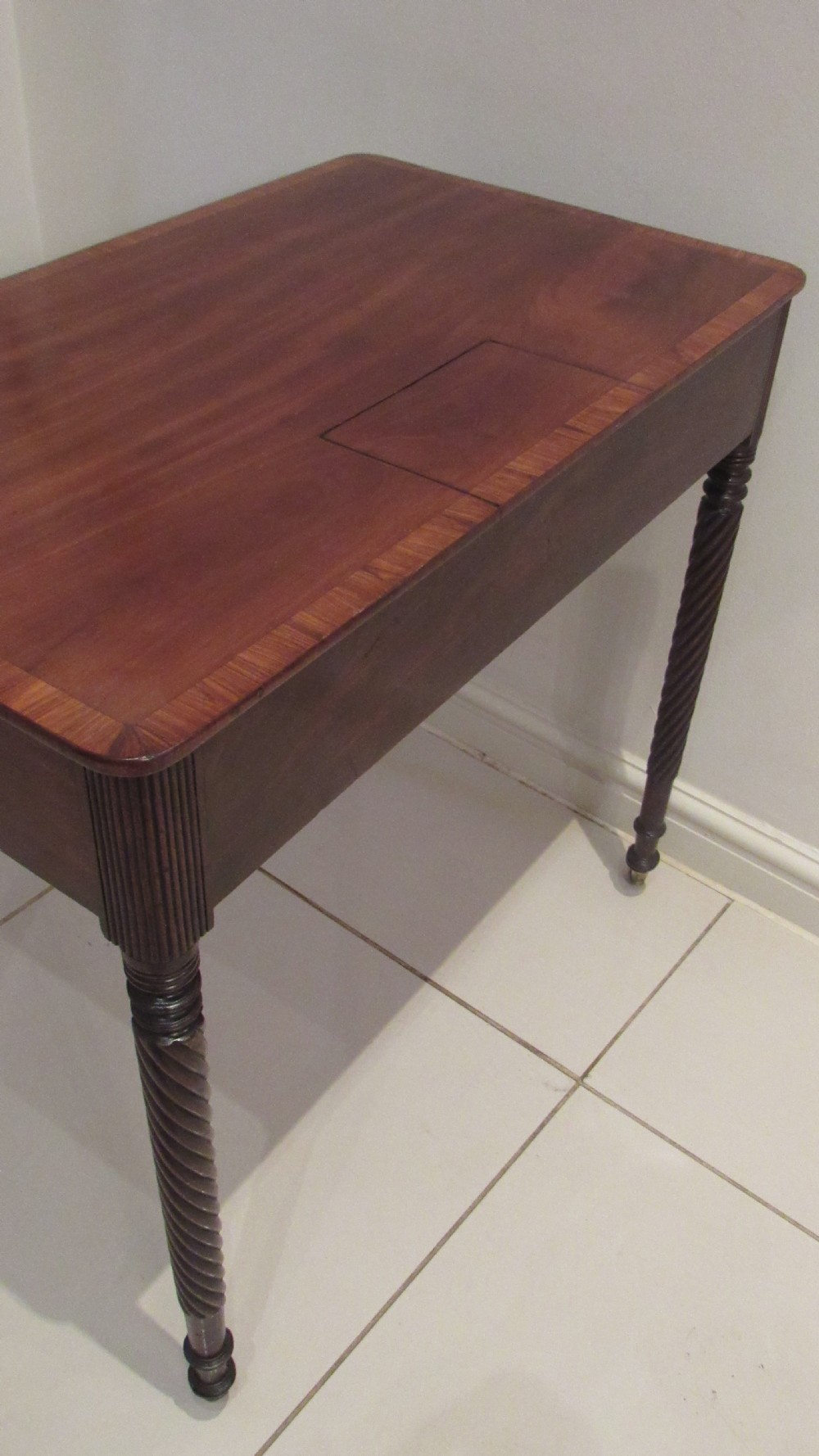 A Georgian mahogany chamber table featuring a rectangular top with a central flap, a single frieze drawer with brass hardware, and spiral turned legs on brass castors. View XVIII