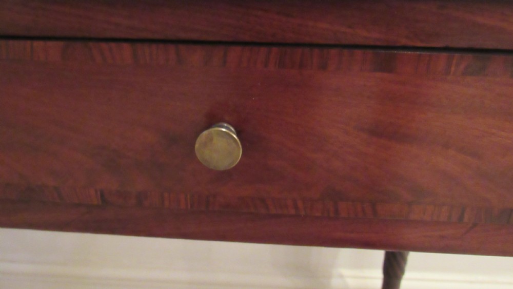 A Georgian mahogany chamber table featuring a rectangular top with a central flap, a single frieze drawer with brass hardware, and spiral turned legs on brass castors. View XX