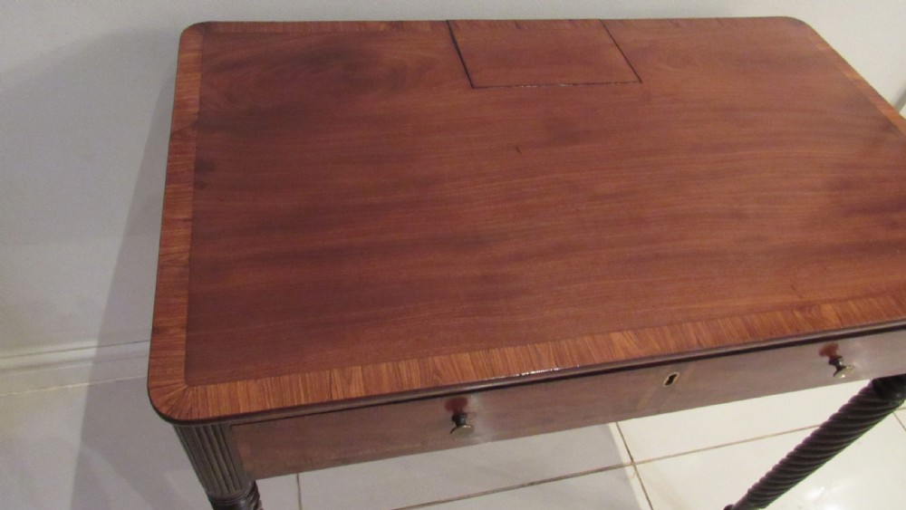 A Georgian mahogany chamber table featuring a rectangular top with a central flap, a single frieze drawer with brass hardware, and spiral turned legs on brass castors. View XXI