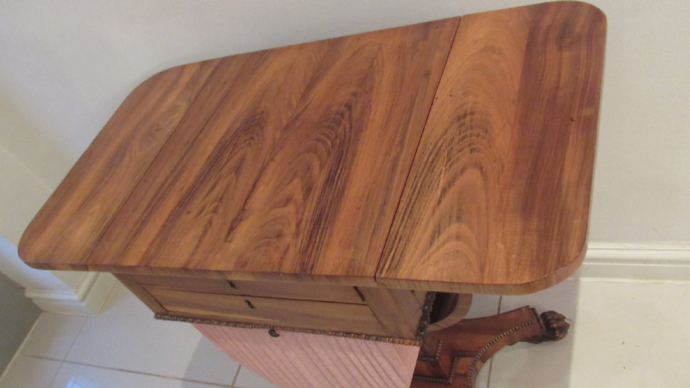 A William IV flame mahogany work table featuring drop-leaf side flaps, drawers with keyholes, a pleated pink fabric work well, and a quadruped base with carved paw feet. View XI