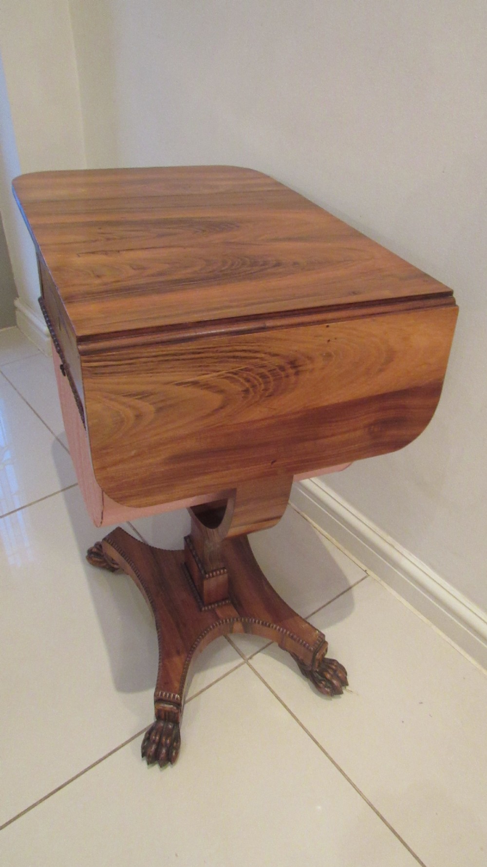 A William IV flame mahogany work table featuring drop-leaf side flaps, drawers with keyholes, a pleated pink fabric work well, and a quadruped base with carved paw feet. View XIV