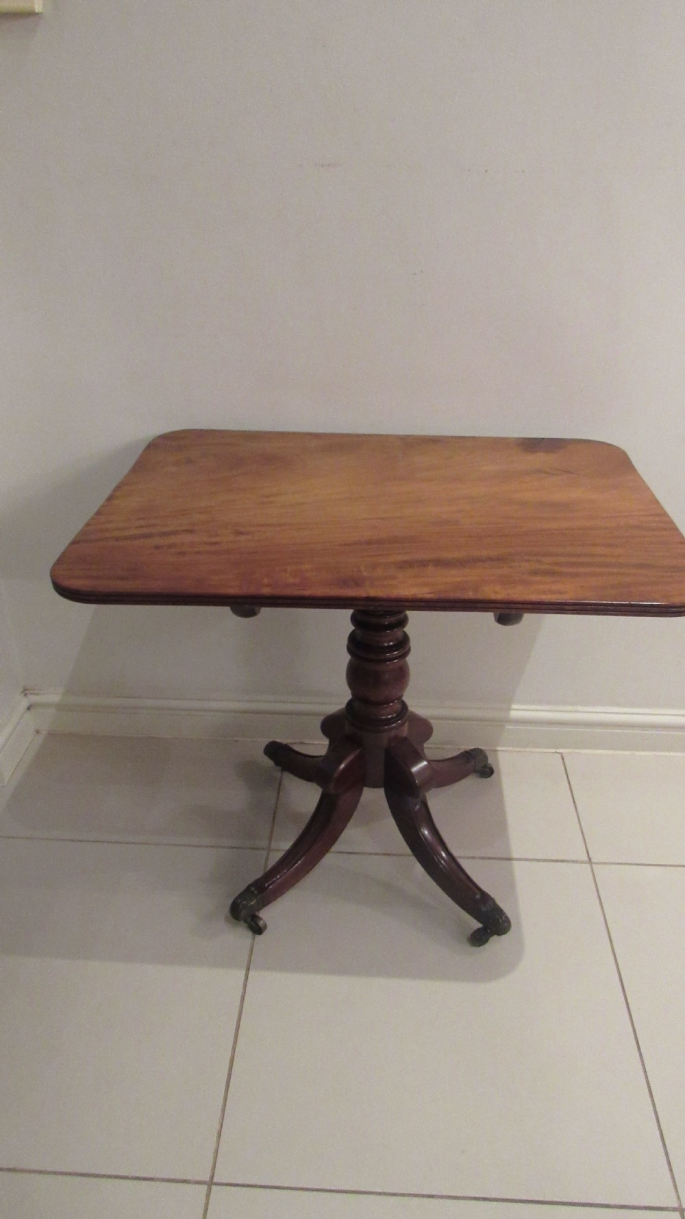 A Regency mahogany side table featuring a rectangular top with rounded corners, a central turned stem, and splayed legs with brass castors. View III