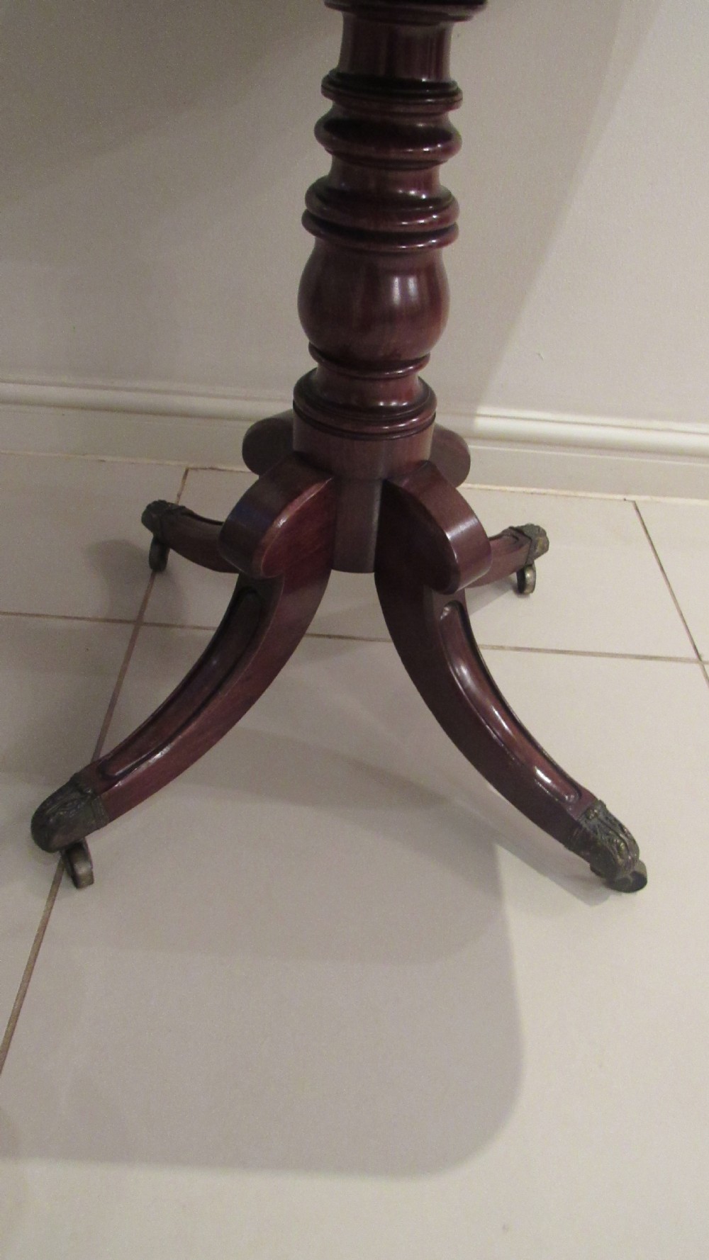 A Regency mahogany side table featuring a rectangular top with rounded corners, a central turned stem, and splayed legs with brass castors. View V