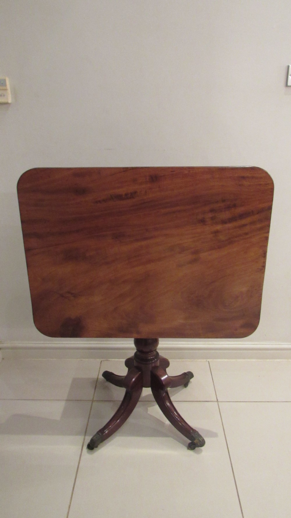 A Regency mahogany side table featuring a rectangular top with rounded corners, a central turned stem, and splayed legs with brass castors. View XII