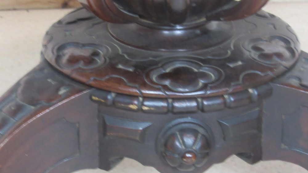 A 19th-century circular rosewood tilt-top table displayed in an upright position, featuring a shaped scalloped rim, prominent book-matched timber grain, and a carved pedestal base. View VIII