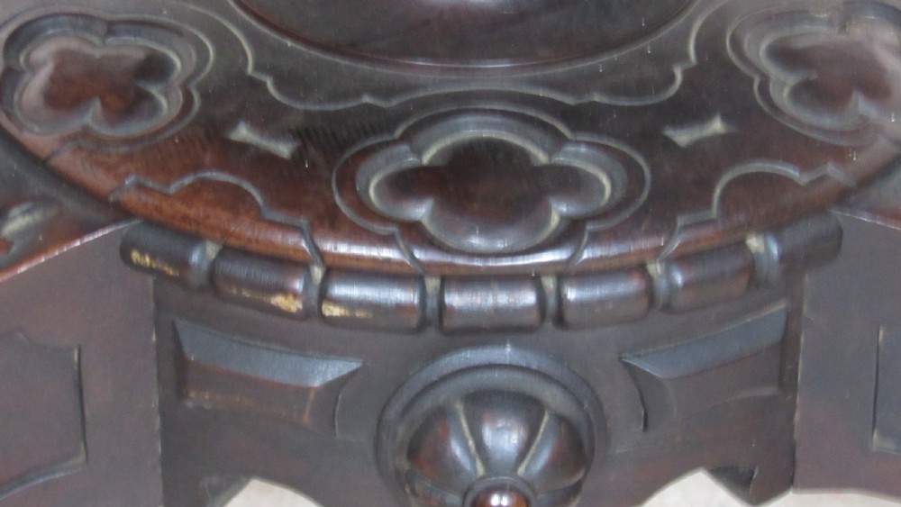 A 19th-century circular rosewood tilt-top table displayed in an upright position, featuring a shaped scalloped rim, prominent book-matched timber grain, and a carved pedestal base. View XI