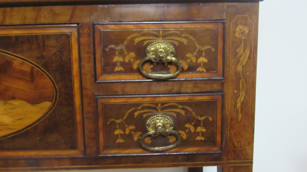 An antique mahogany glazed display cabinet featuring marquetry inlay, two glass doors, four small drawers, and square tapered legs. View VIII