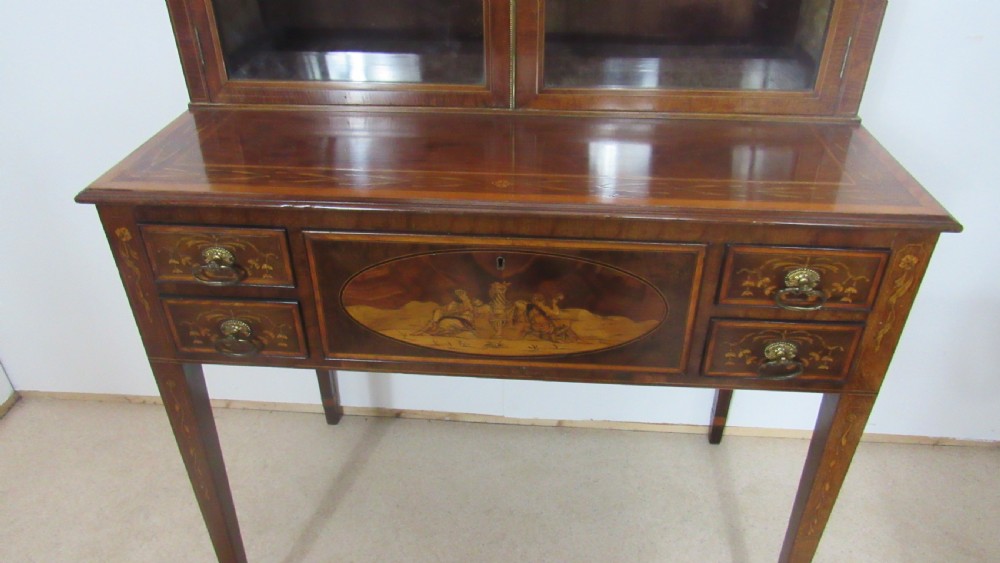 An antique mahogany glazed display cabinet featuring marquetry inlay, two glass doors, four small drawers, and square tapered legs. View XIV