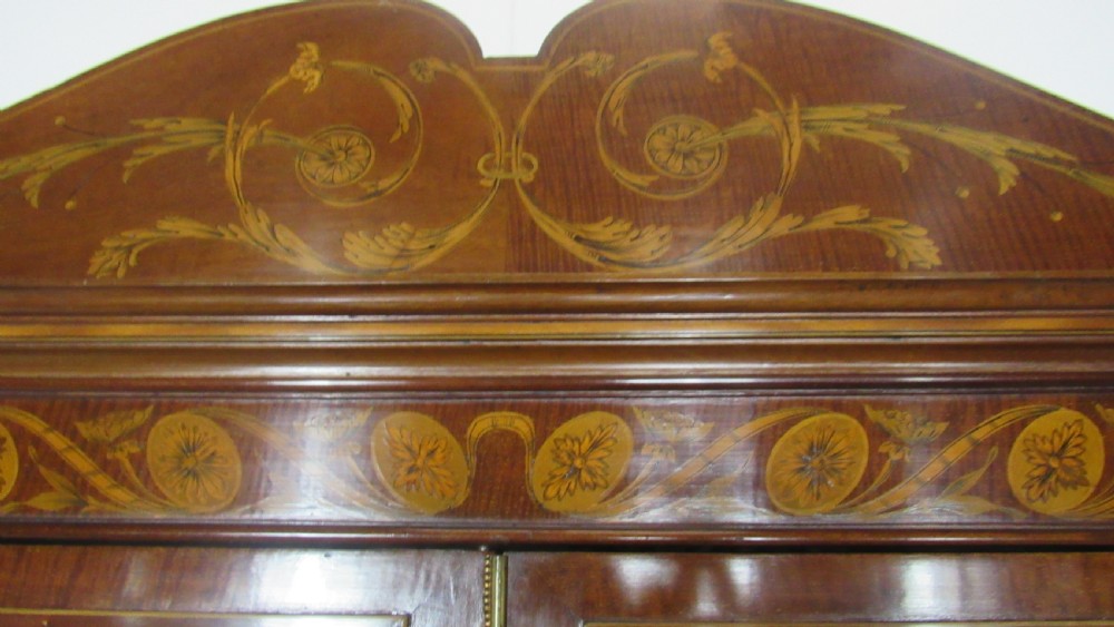 An antique mahogany glazed display cabinet featuring marquetry inlay, two glass doors, four small drawers, and square tapered legs. View XVI