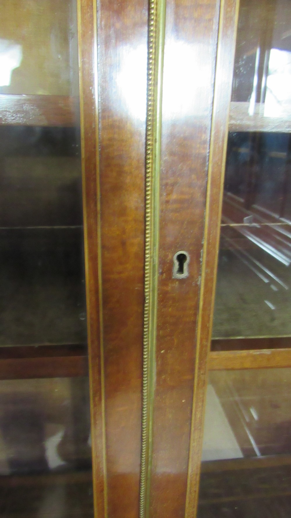 An antique mahogany glazed display cabinet featuring marquetry inlay, two glass doors, four small drawers, and square tapered legs. View XVII