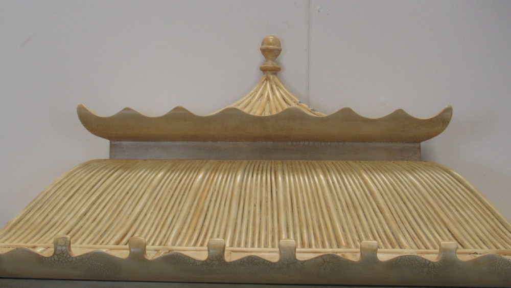 A cream painted Chinoiserie display cabinet on a stand featuring a pagoda-style roof, diamond lattice glass doors, and faux bamboo detailing. View VI