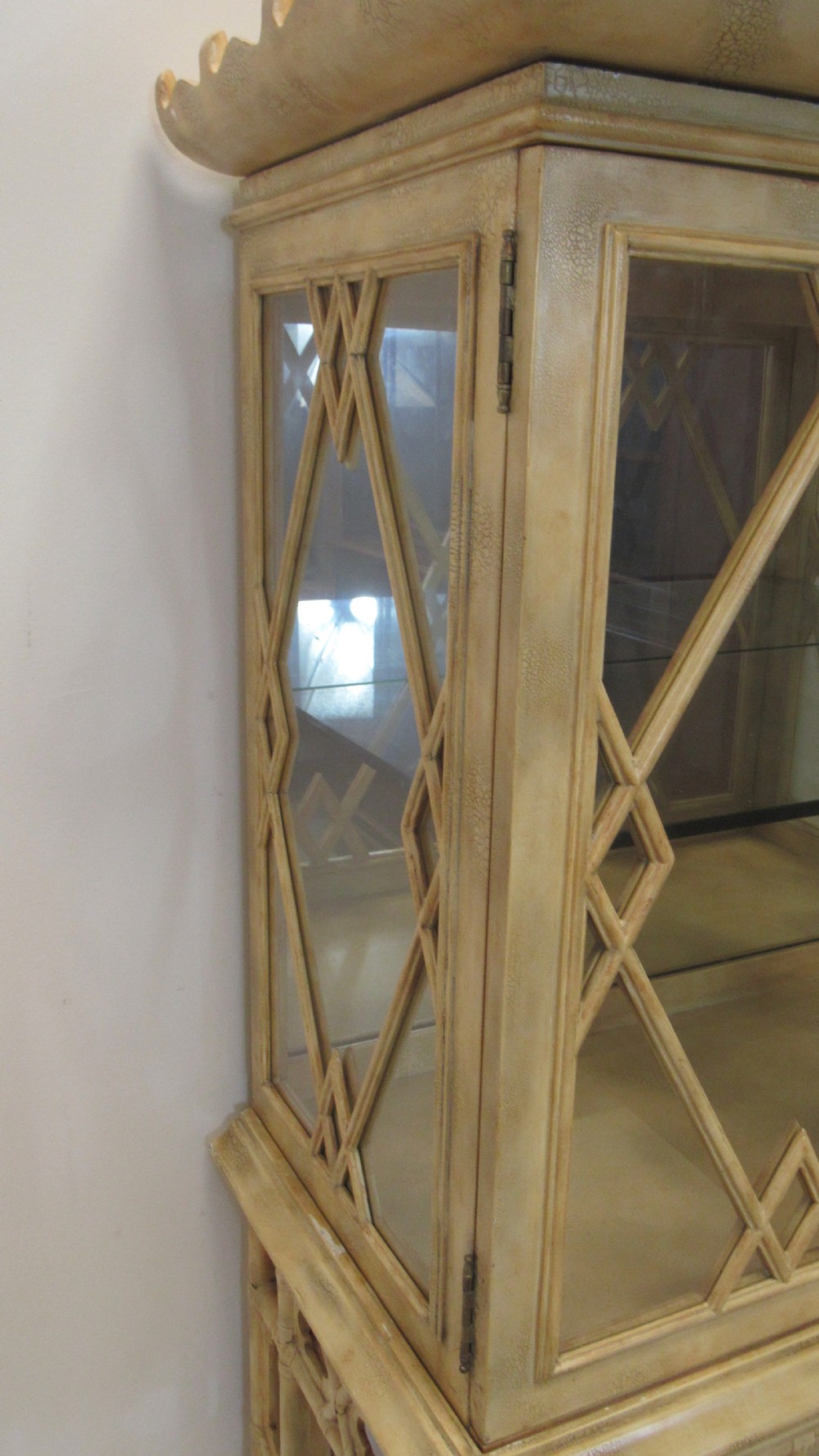 A cream painted Chinoiserie display cabinet on a stand featuring a pagoda-style roof, diamond lattice glass doors, and faux bamboo detailing. View XV