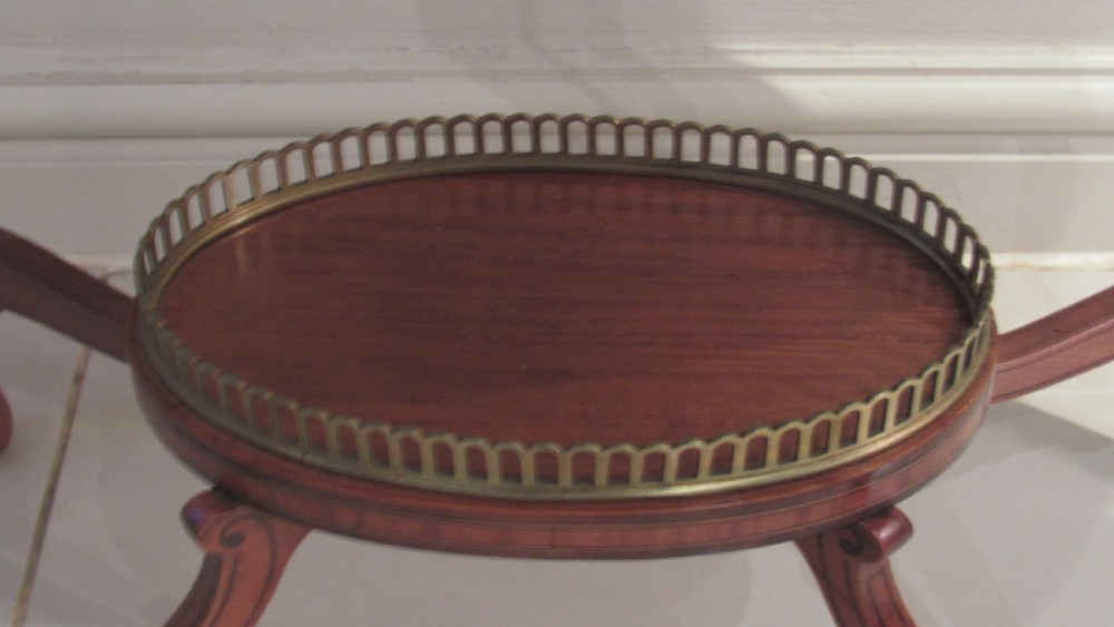 An oval antique satinwood occasional table featuring decorative marquetry inlay on top, tapered legs, and a small lower shelf with a brass gallery rail. View VIII