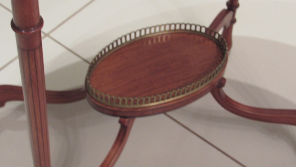 An oval antique satinwood occasional table featuring decorative marquetry inlay on top, tapered legs, and a small lower shelf with a brass gallery rail. View XIV