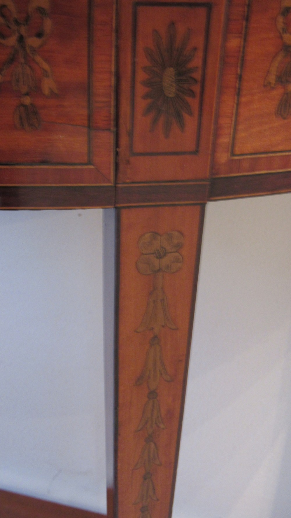 A semi-circular golden satinwood demilune console table featuring urn marquetry inlay, slender tapered legs, and an under-tier shelf. View VI