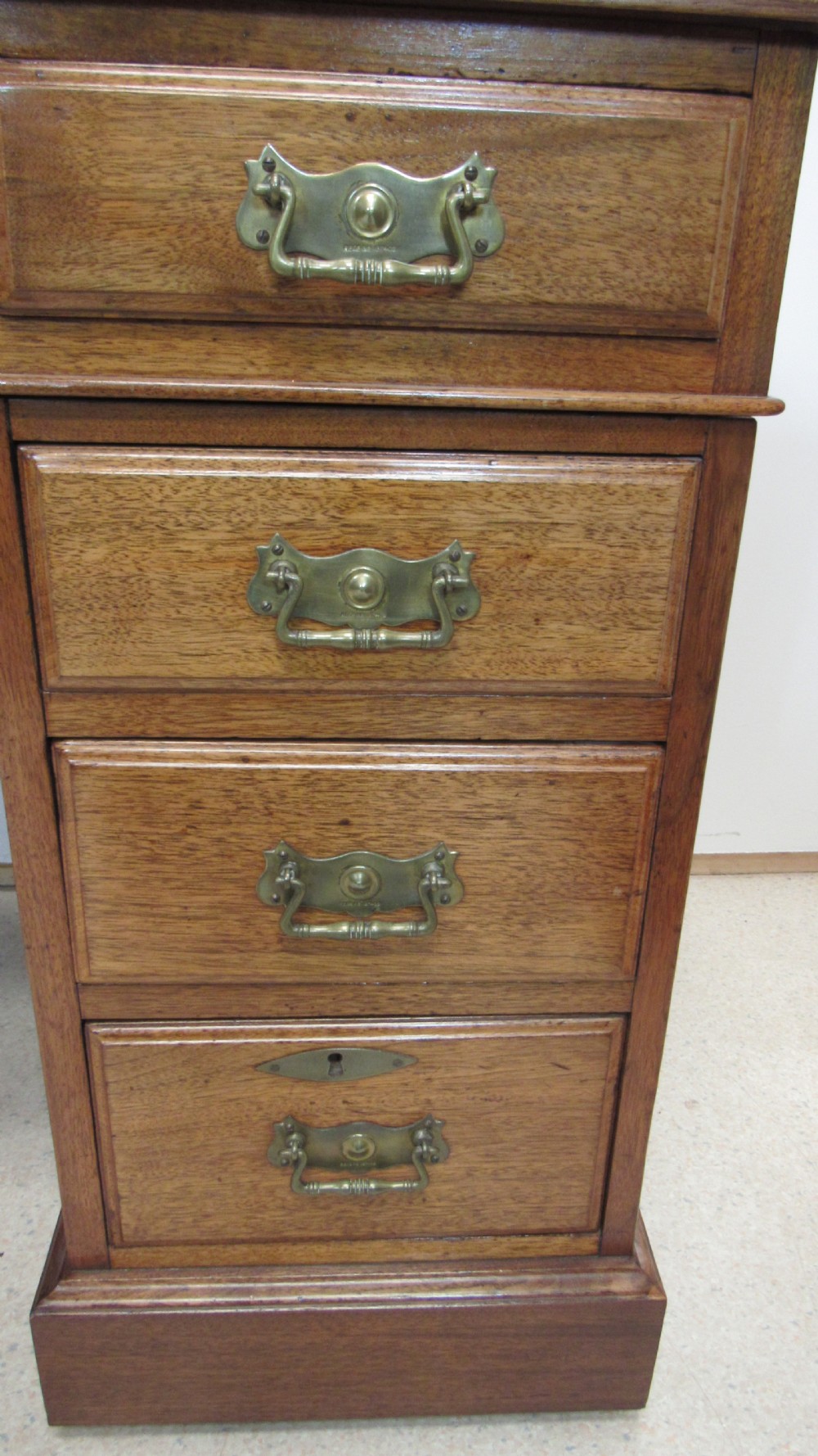A red walnut pedestal desk featuring a gold-tooled red leather insert writing top, twin drawer pedestals, and brass drop handles. View VIII