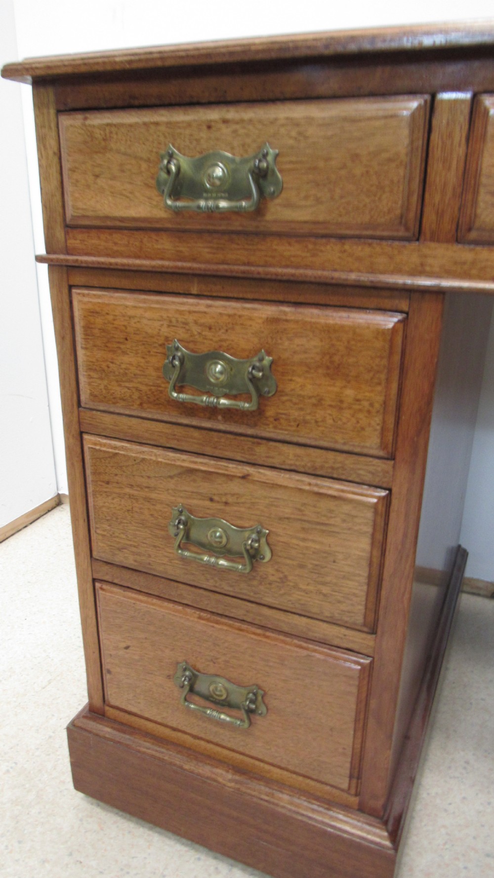 A red walnut pedestal desk featuring a gold-tooled red leather insert writing top, twin drawer pedestals, and brass drop handles. View IX