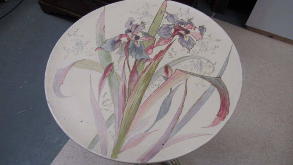 A circular Art Nouveau pottery table featuring a hand-painted floral iris design on a cream-glazed top supported by a sculpted pedestal base. View II
