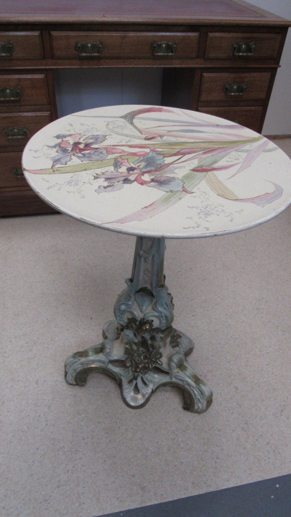 A circular Art Nouveau pottery table featuring a hand-painted floral iris design on a cream-glazed top supported by a sculpted pedestal base. View VI