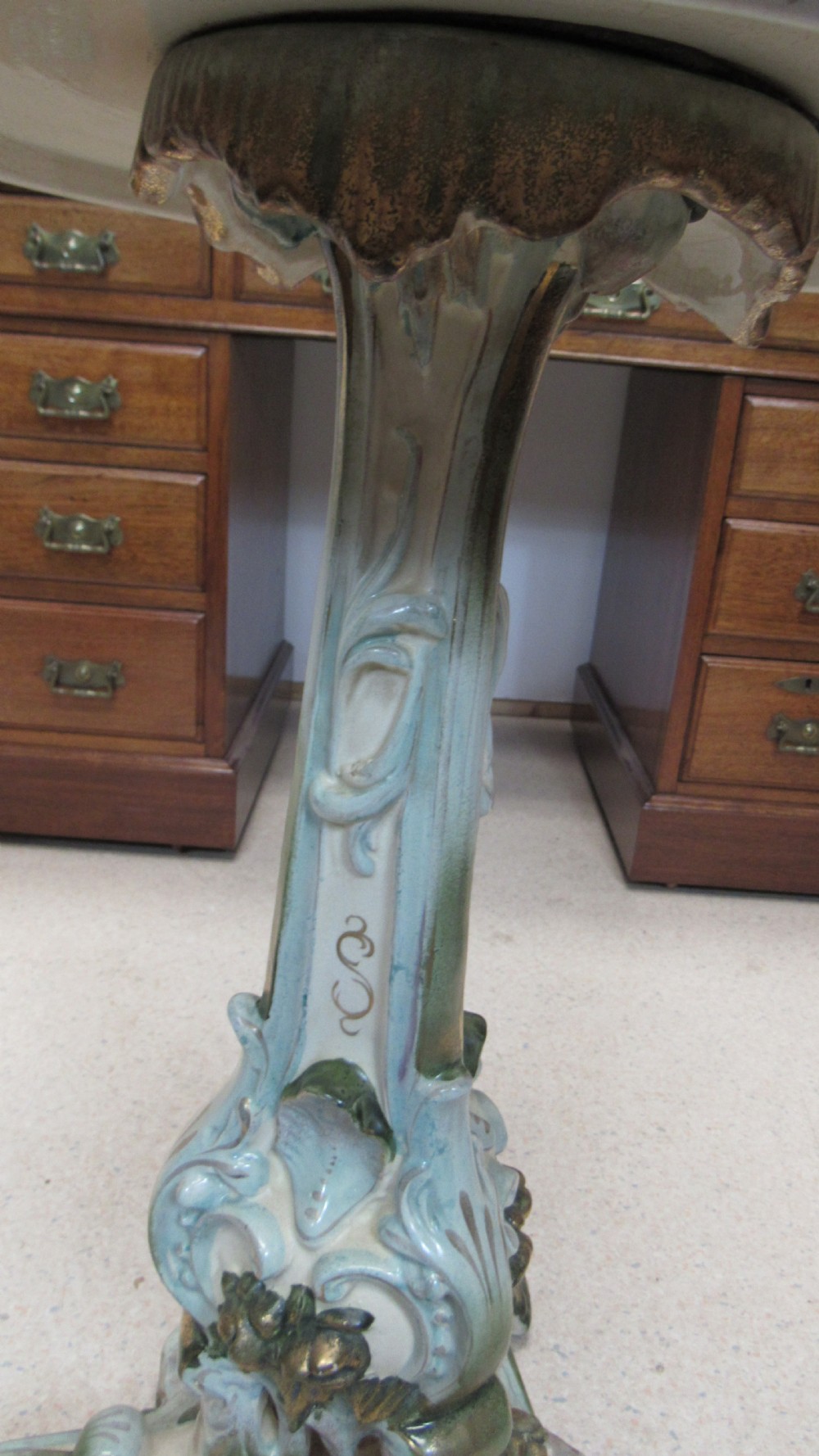 A circular Art Nouveau pottery table featuring a hand-painted floral iris design on a cream-glazed top supported by a sculpted pedestal base. View XV