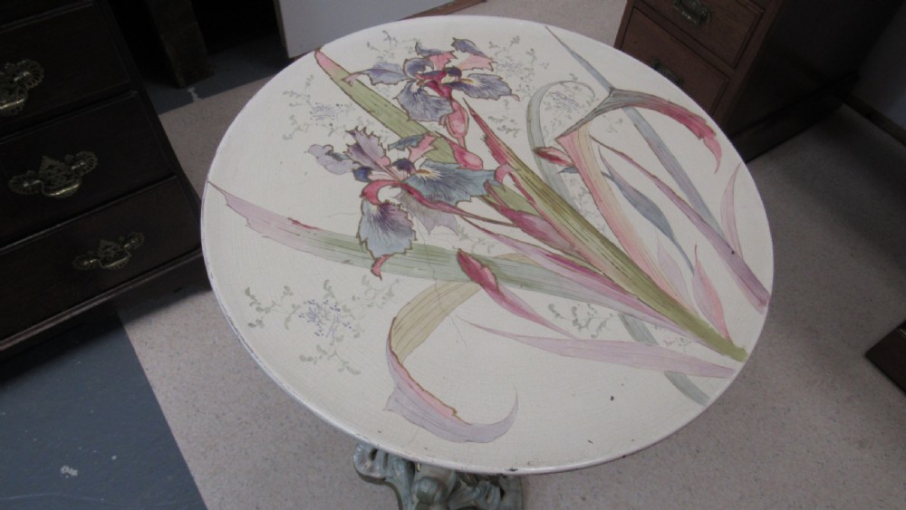 A circular Art Nouveau pottery table featuring a hand-painted floral iris design on a cream-glazed top supported by a sculpted pedestal base. View XVIII