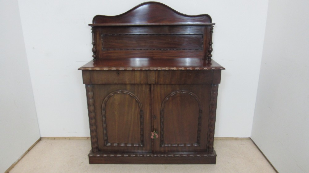 A Victorian mahogany chiffonier featuring an upper gallery shelf with turned side supports above a two-door lower cabinet with arched moulded panels.