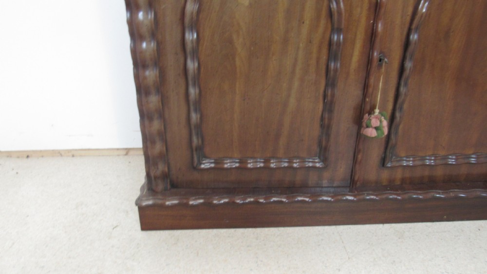 A Victorian mahogany chiffonier featuring an upper gallery shelf with turned side supports above a two-door lower cabinet with arched moulded panels. View X