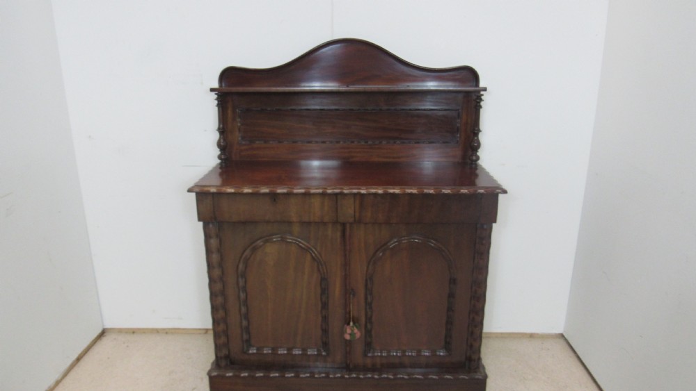 A Victorian mahogany chiffonier featuring an upper gallery shelf with turned side supports above a two-door lower cabinet with arched moulded panels. View XVI