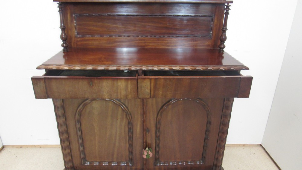 A Victorian mahogany chiffonier featuring an upper gallery shelf with turned side supports above a two-door lower cabinet with arched moulded panels. View XIX